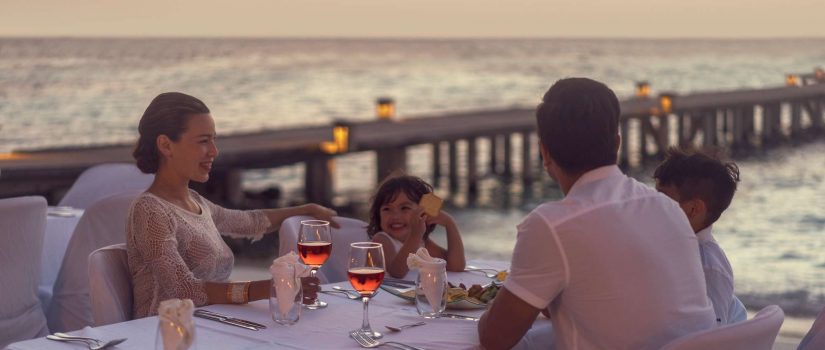 Club Med Kani, aux Maldives - Une famille profitant d'un repas en soirée, sur une terrasse extérieure. 