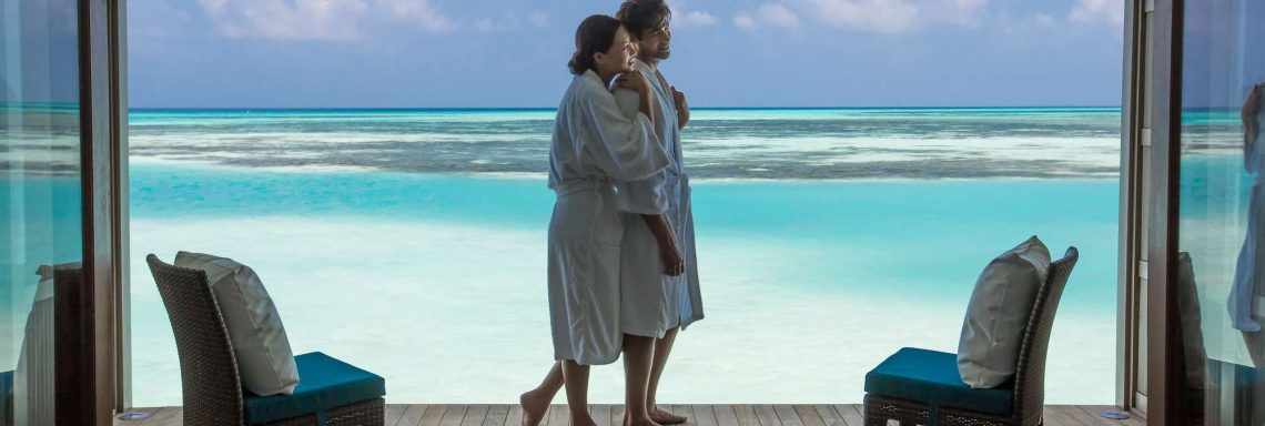Club Med Villas de FInolhu, aux Maldives - Photo d'un couple sur la terrasse d'une villa devant la lagune bleu turquoise