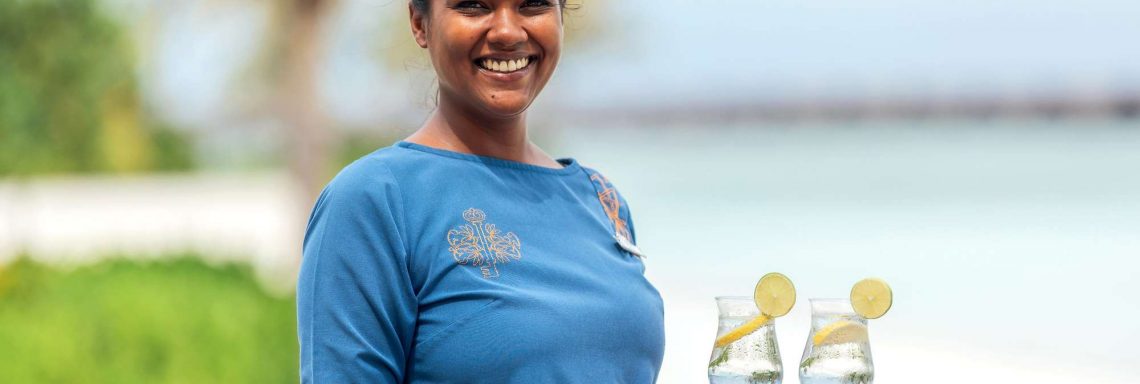 Club Med Villas de FInolhu, aux Maldives - Photo d'une employée du Club Med servant des cocktail sur la plage