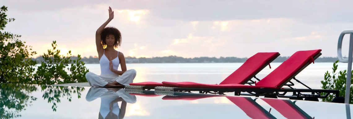 Club Med Sandpiper Bay, Floride - une femme fait du yoga en mâtiné, sur le bord de la piscine 